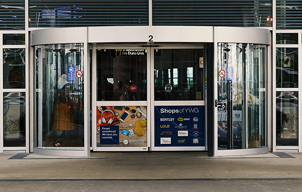 Photo of the main revolving doors of the airport, showing design posters we created that sit inside of the doors as people enter the building.